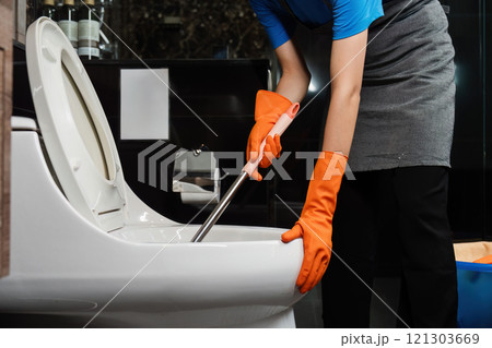 Cleaning online service. yong woman housekeeper cleaning flush toilet in bathroom with toilet brush. House cleaning service concept 121303669