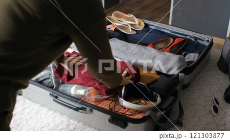 Young woman carefully organizes clothes and cosmetics while packing for her business trip or weekend getaway 121303877