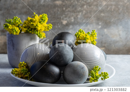 Black Easter eggs Elegant Ceramic Spheres with Yellow Flowers on Table Black Easter eggs Elegant Ceramic Spheres with Yellow Flowers on Table 121303882