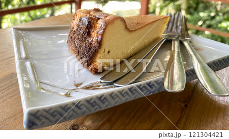 piece of cheesecake on a plate with forks on a wooden tabletop 121304421