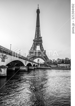 The Eiffel Tower stands majestically above the Seine River at dawn, casting a stunning reflection. Early morning light enhances the beauty of this iconic landmark in Paris, offering a serene view. 121304492