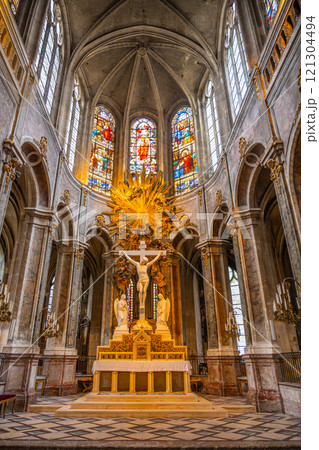The grandeur of Saint-Merri's interior displays stunning architecture, intricate stained glass, and a striking altar featuring a crucifix, illuminating the sacred atmosphere of this Parisian landmark. 121304494