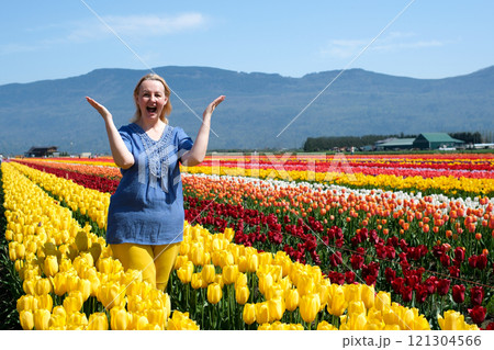 Young woman with long wavy hair enjoying a vibrant tulip garden on a sunny day, wearing sunglasses and a stylish black outfit Young woman with long wavy hair enjoying a vibrant tulip garden on a sunny day, wearing sunglasses and a stylish black outfit 121304566