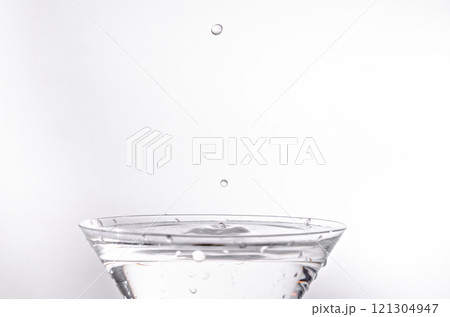 Close up of water drop falling into a glass on white background	 121304947