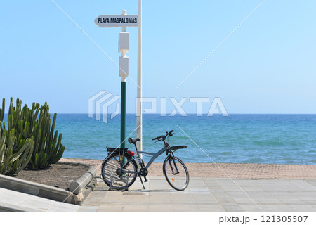 Bicycle parked on the promenade at the background of the sea in Maspalomas, Gran Canaria, Canary Islands, Spain Bicycle parked on the promenade at the background of the sea in Maspalomas, Gran Canaria, Canary Islands, Spain 121305507