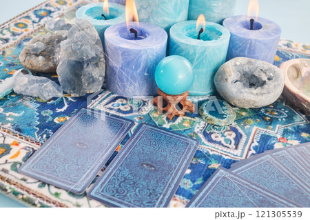 Mystical Card Reading Setup. Blue candles, crystals, and tarot cards on a patterned cloth. 121305539
