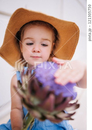 Cute little girl holding big artichoke flower in hands Cute little girl holding big artichoke flower in hands 121305750
