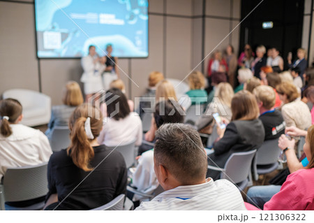 Audience attentively listening during a professional presentation in a modern conference room 121306322