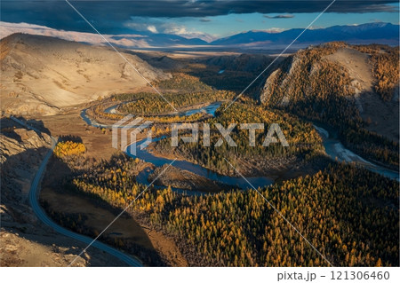 Aerial view of meandering river through forested and mountainous autumn landscape Aerial view of meandering river through forested and mountainous autumn landscape 121306460