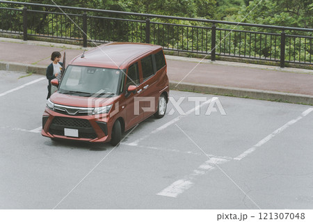 駐車場に停めた車に乗り込む女性 駐車場に停めた車に乗り込む女性 121307048