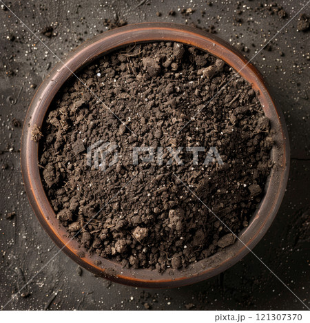 Rich, dark soil fills a terracotta pot, showing texture and potential for gardening at a vibrant outdoor location Rich, dark soil fills a terracotta pot, showing texture and potential for gardening at a vibrant outdoor location 121307370