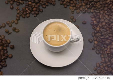 white cup with espresso coffee on a saucer with coffee beans on a dark background white cup with espresso coffee on a saucer with coffee beans on a dark background 121308840