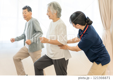 デイサービスで運動するシニアの男女と理学療法士・作業療法士・ケアマネージャーの女性 デイサービスで運動するシニアの男女と理学療法士・作業療法士・ケアマネージャーの女性 121308871