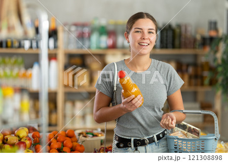 Woman choosing peach juice in supermarket 121308898