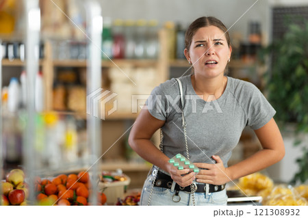Woman in the store holding her stomach 121308932
