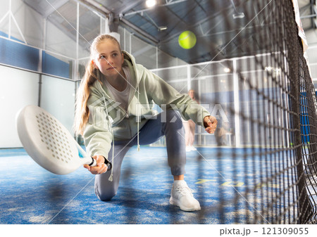 Teenager girl plays paddle. View through grid 121309055
