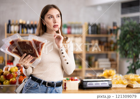 Young woman choosing jamon in grocery store 121309079