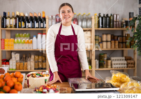 Portrait of female seller in an apron behind the counter of grocery store 121309147