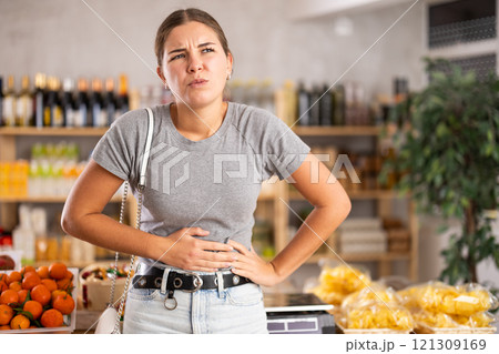 Woman in the store holding her stomach Woman in the store holding her stomach 121309169