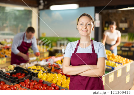 Positive and friendly store woman employee stands with arms crossed on chest and waits for customers 121309413