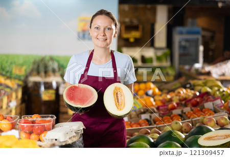 Woman grocery store seller offers a choice of buying ripe melon or watermelon. Woman grocery store seller offers a choice of buying ripe melon or watermelon. 121309457