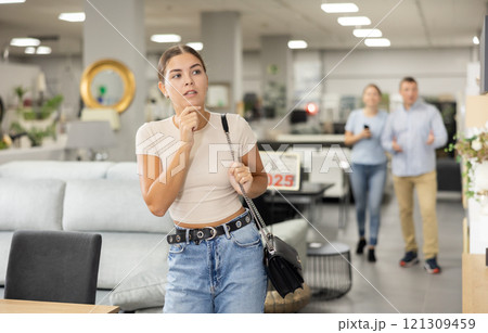 Positive female shopper choosing new upholstered furniture in furniture store Positive female shopper choosing new upholstered furniture in furniture store 121309459