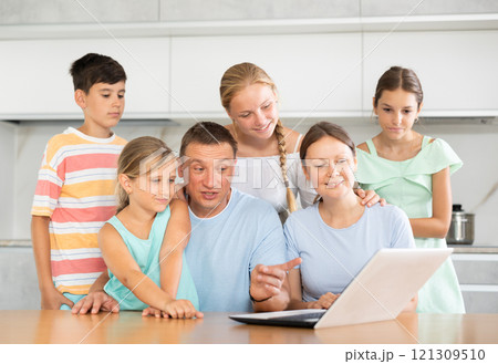 Large family uses a laptop to communicate with friends and relatives via Internet 121309510