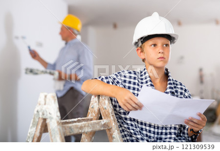 Boy reading documents in house being renovating Boy reading documents in house being renovating 121309539
