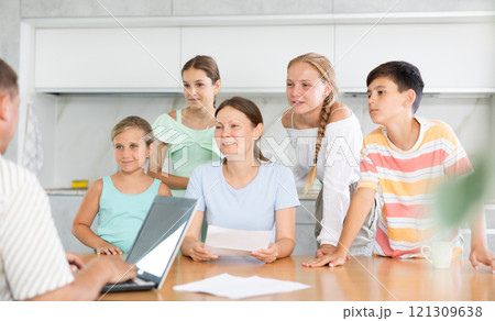 Man is typing on laptop and listening to joyful wife read aloud letter to her family. 121309638