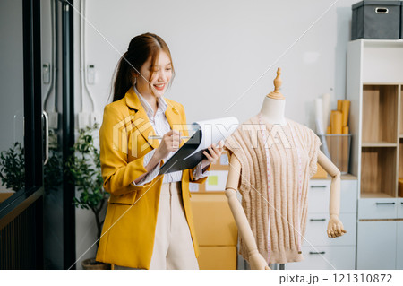 Asian tailor woman working on clothes in tailoring atelier. beautiful young female fashion designer smile 121310872