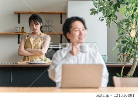 テレワークする夫をキッチンで不機嫌そうに睨む主婦・妻（喧嘩・イライラ・ストレス） 121310891