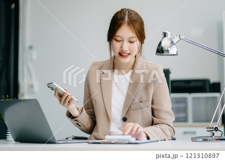 Asian businesswoman working with working notepad, tablet and laptop documents talking on the smartphone, tablet and laptop video call tax Asian businesswoman working with working notepad, tablet and laptop documents talking on the smartphone, tablet and laptop video call tax 121310897