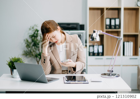 Asian woman feeling migraine head strain.Overworked businesswoman financier while working Asian woman feeling migraine head strain.Overworked businesswoman financier while working 121310902