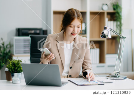 Asian Businesswoman Analyzing Finance on Tablet and Laptop at modern Office Desk tax Asian Businesswoman Analyzing Finance on Tablet and Laptop at modern Office Desk tax 121310929