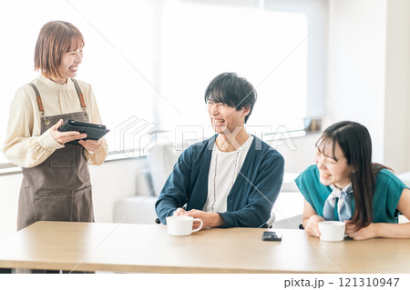 おしゃれなカフェでオーダーを取るスタッフとカップル 121310947