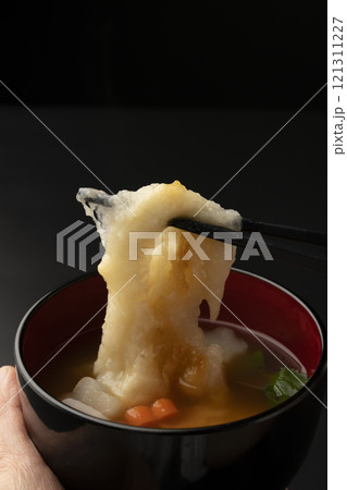 お雑煮のお椀を手で持ち餅を箸で持ち上げる お雑煮のお椀を手で持ち餅を箸で持ち上げる 121311227