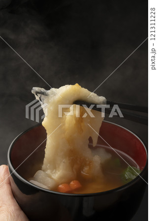 お雑煮のお椀を手で持ち餅を箸で持ち上げる お雑煮のお椀を手で持ち餅を箸で持ち上げる 121311228