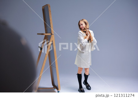 A captivating portrait of a young girl in a studio, showcasing her mirror reflection A captivating portrait of a young girl in a studio, showcasing her mirror reflection 121311274