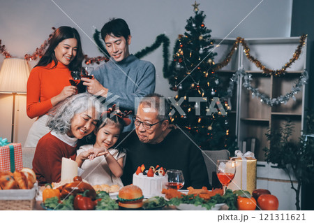 Multi-Generation Family Celebrate Christmas At Home Wearing Santa Hats And Antlers Opening Presents 121311621