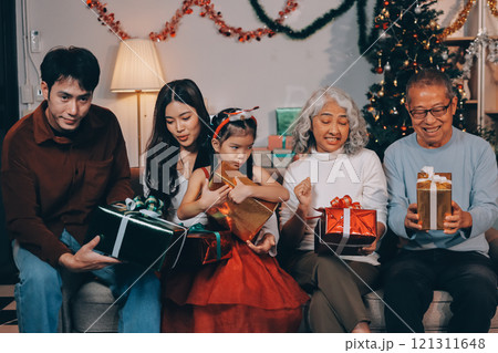 Portrait of Asian family exchanging presents during christmas at home. Attractive happy people holding gift box, celebrate holiday thanksgiving, xmas eve tradition in living room in house together. Portrait of Asian family exchanging presents during christmas at home. Attractive happy people holding gift box, celebrate holiday thanksgiving, xmas eve tradition in living room in house together. 121311648