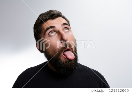 Man with beard sticking out tongue and looking up 121312060