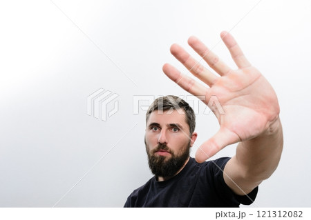 Man with beard holding hand up in front of face 121312082