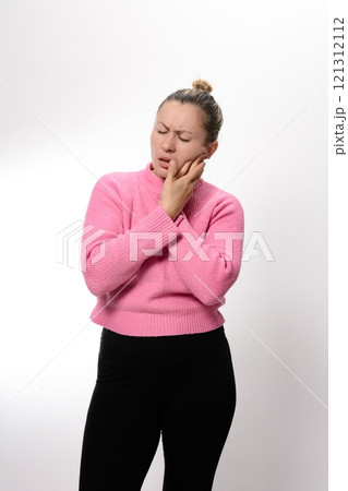 Woman experiencing toothache, holding her jaw in pain. 121312112