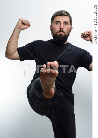 Man kicking towards camera with fists raised Man kicking towards camera with fists raised 121312528