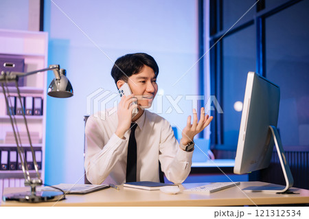 Overtime work concept, Handsome asian business man working overtime sitting at desk using computer and doing overtime project 121312534