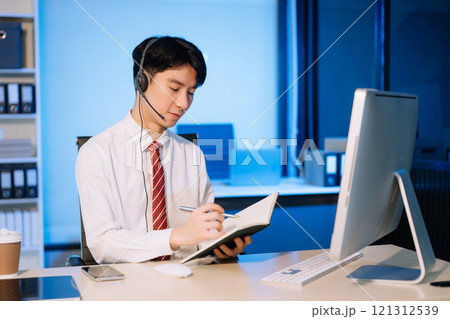 Serious call center operator in wireless headset talking with customer, Asian man with microphone consulting client on phone in customer support service 121312539