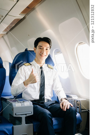 Asian Confident male pilot in uniform leaning at the passenger seat while standing inside of the airplane flight 121312832
