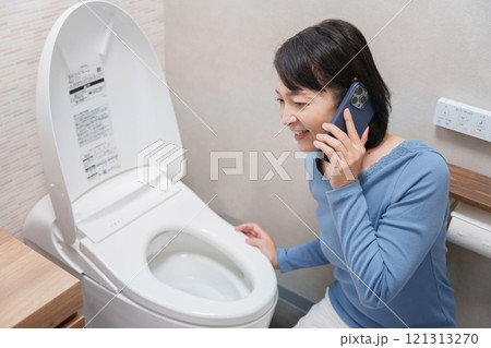 トイレのトラブルで水道業者に電話する女性 121313270