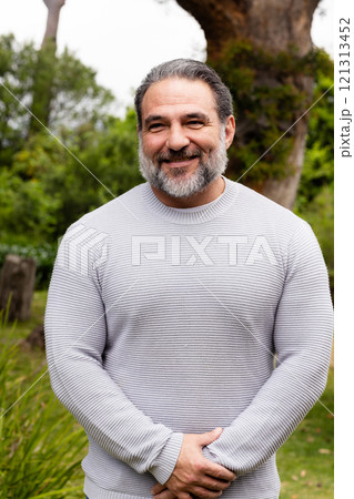 Smiling mature man standing outdoors in garden, enjoying peaceful day Smiling mature man standing outdoors in garden, enjoying peaceful day 121313452