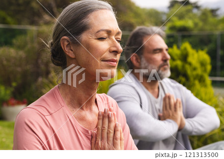 Mature couple meditating outdoors, enjoying peaceful moment in nature together 121313500